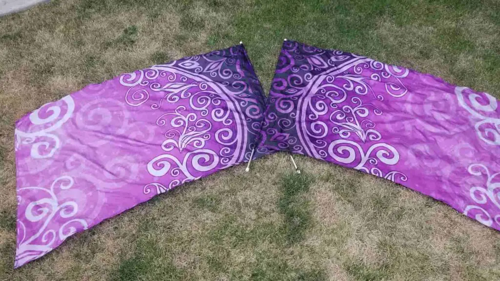 Two purple swing flags for color guard lying on the grass 