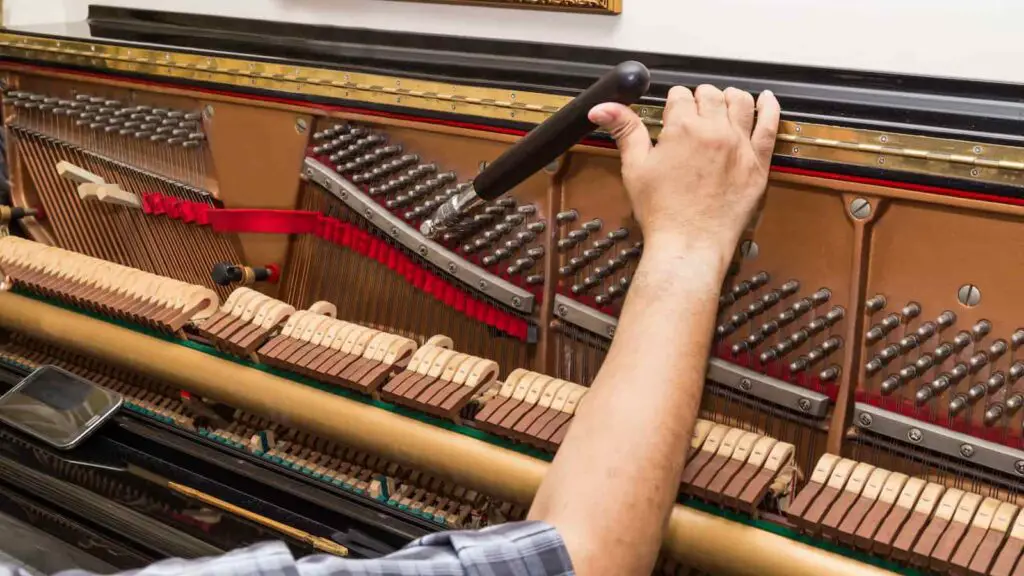 close up on hand tuning an upright piano
