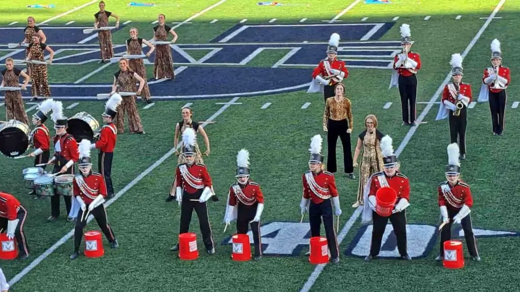 Marching band percussion line playing on red buckets. 