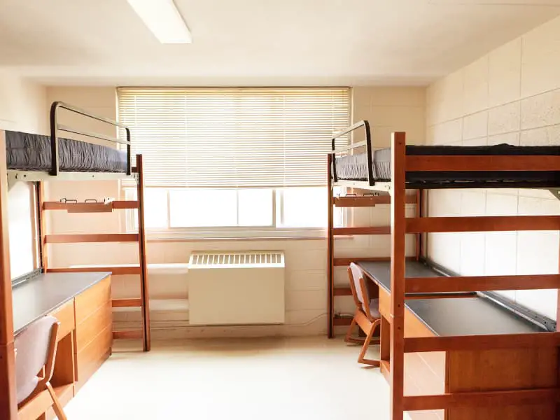 College dorm room with bunk bed on top and desk underneath. 