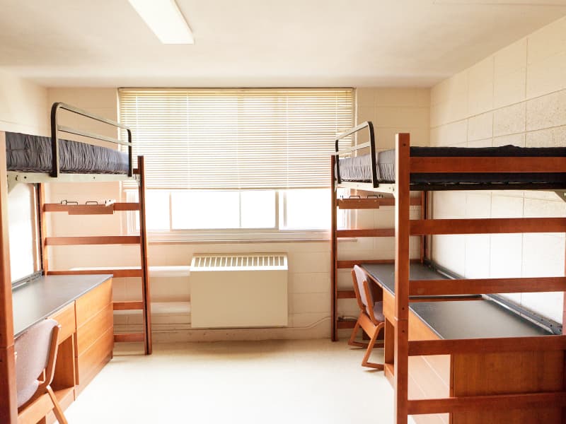 College dorm room with bunk bed on top and desk underneath. 