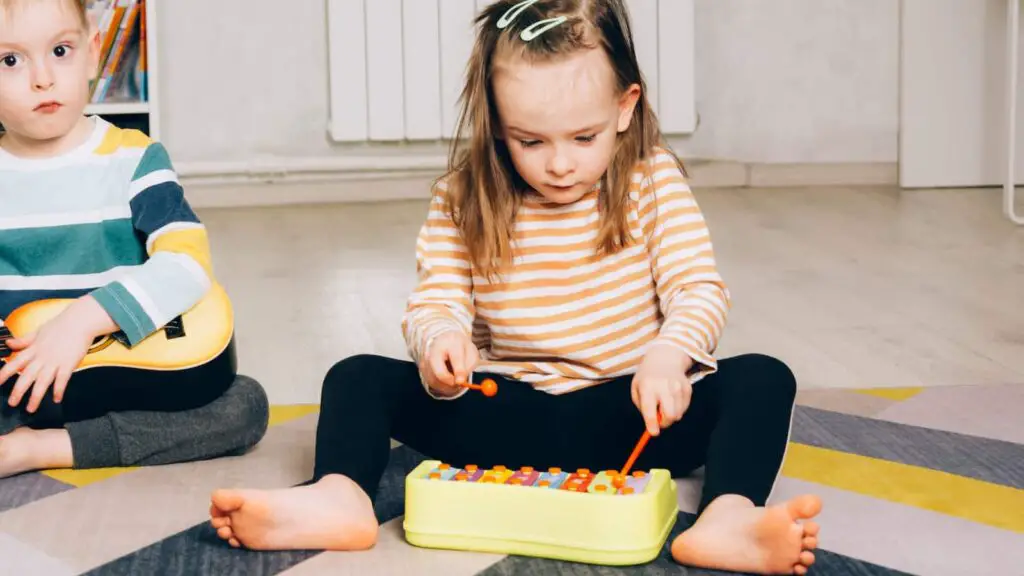 Child sitting on the floor learning how to play the Xylophone