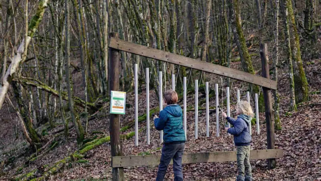 Xylophone musical instrument hanging in the forest being played by two children. 