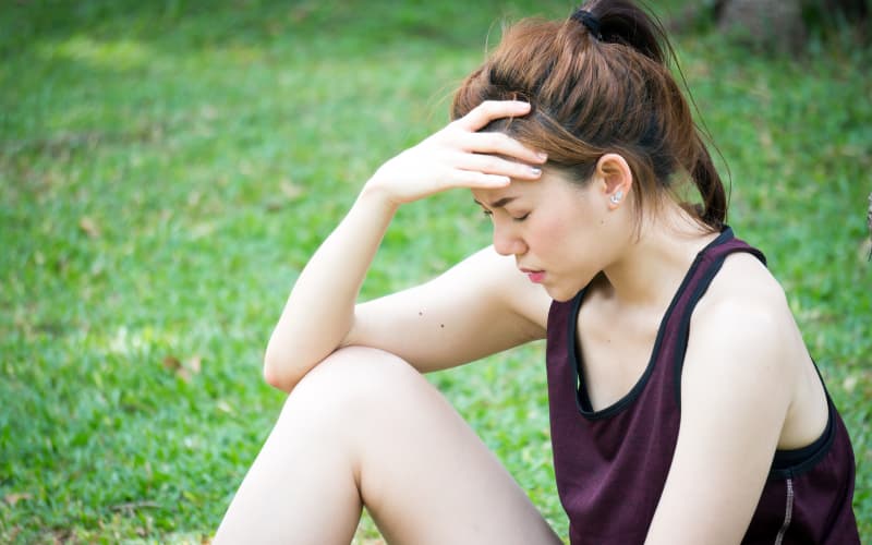 girl sitting on grass about to faint