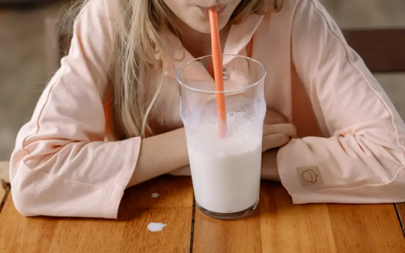 Girl in pink pajamas drinking milk