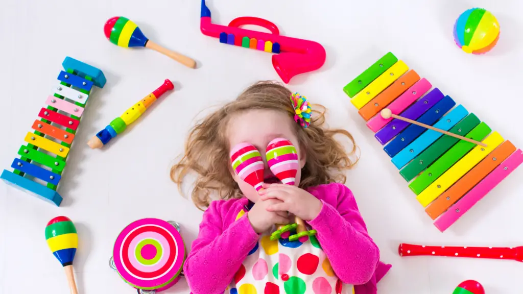 Toddler laying in the middle of musical toys like xylophones. 